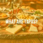 Assortment of Spanish tapas on a wooden table, vibrant colors, olives, cheese, chorizo, bread, cozy bar setting, social dining atmosphere, realistic.
